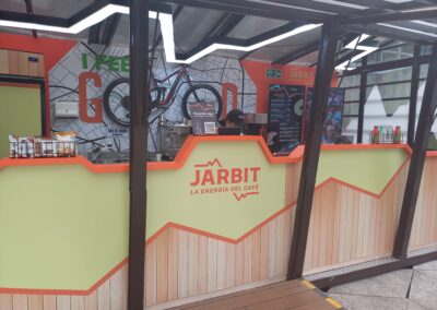 Diseñamos un espacio con un concepto que refleja modernidad y riesgo. Elementos Destacados del Diseño: Iluminación a traves de una lampara led diseñada espacialmente para Jarbit. Counter de atención con materiales aptos para la manipulación de alimentos. Muro impacto con un mensaje que guarda diferenciación en sus elementos.