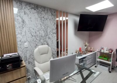 Escritorio sencillo en vidrio con patas cromadas. Apliques en madera con diseño. Pared marmolizada con tiras de espejo en color palo de rosa que refleja sofisticación y elegancia. Colores según identidad de marca.
