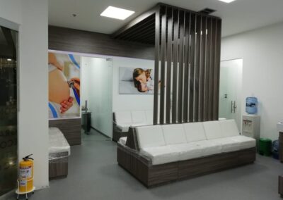 Sala de espera moderna con muebles en tonos neutros, paneles divisorios de madera y gráficos médicos – Proyecto de diseño interior por Brandinn. Elementos Destacados del Diseño: Mobiliario en tonos cálidos y neutros, generando confort y elegancia. Panel divisor decorativo en madera, brindando privacidad sin aislar los espacios. Gráficos temáticos en paredes, reforzando la identidad del centro médico. Iluminación estratégica y materiales higiénicos, priorizando la funcionalidad y bienestar.