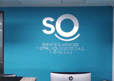 Logo en acrílico con acabado brush metalizado en pared azul – Remodelación de local comercial SO S.A.S. por Brandinn